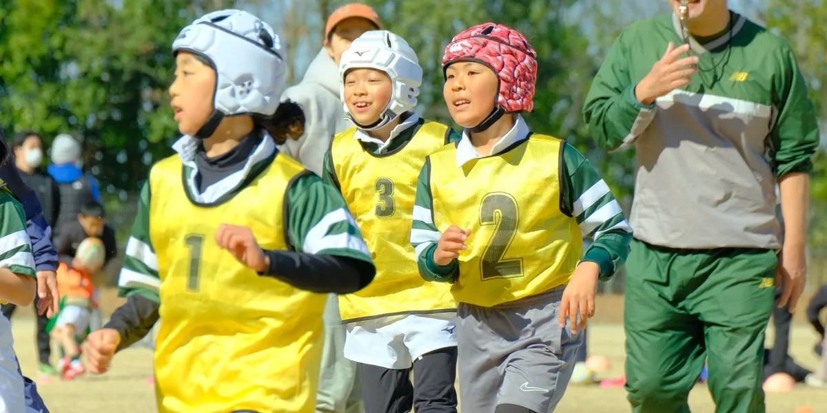 子どもたちがグラウンドでラグビーの練習をしている様子